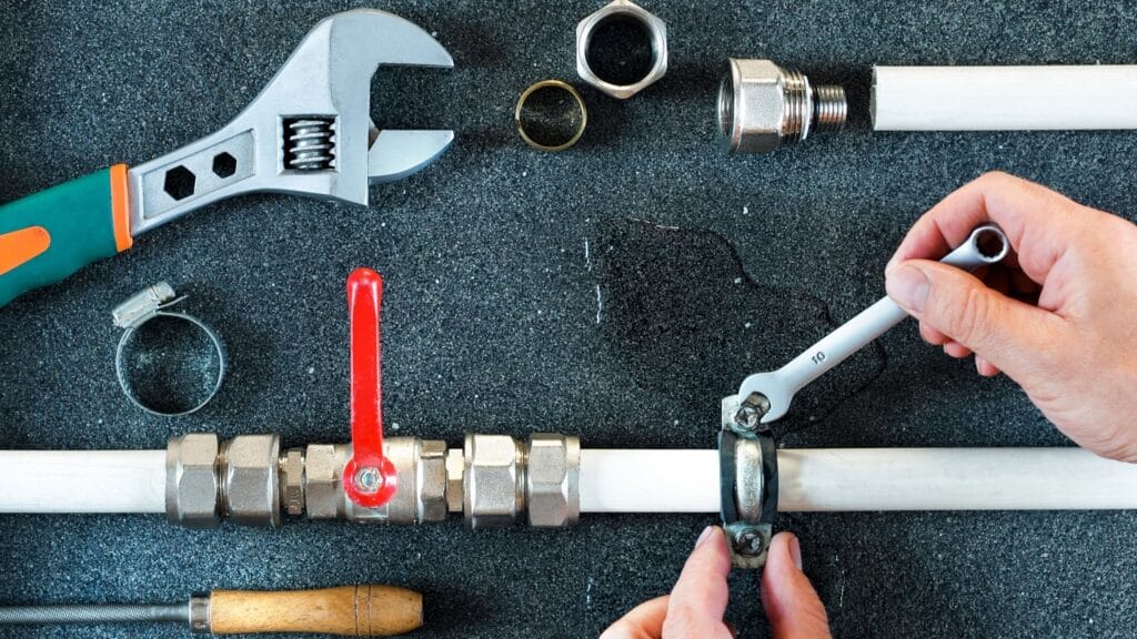 Plumber repairing a pipe valve with an adjustable wrench in Camas