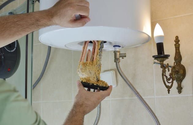 Technician removing mineral buildup from a water heater in Camas
