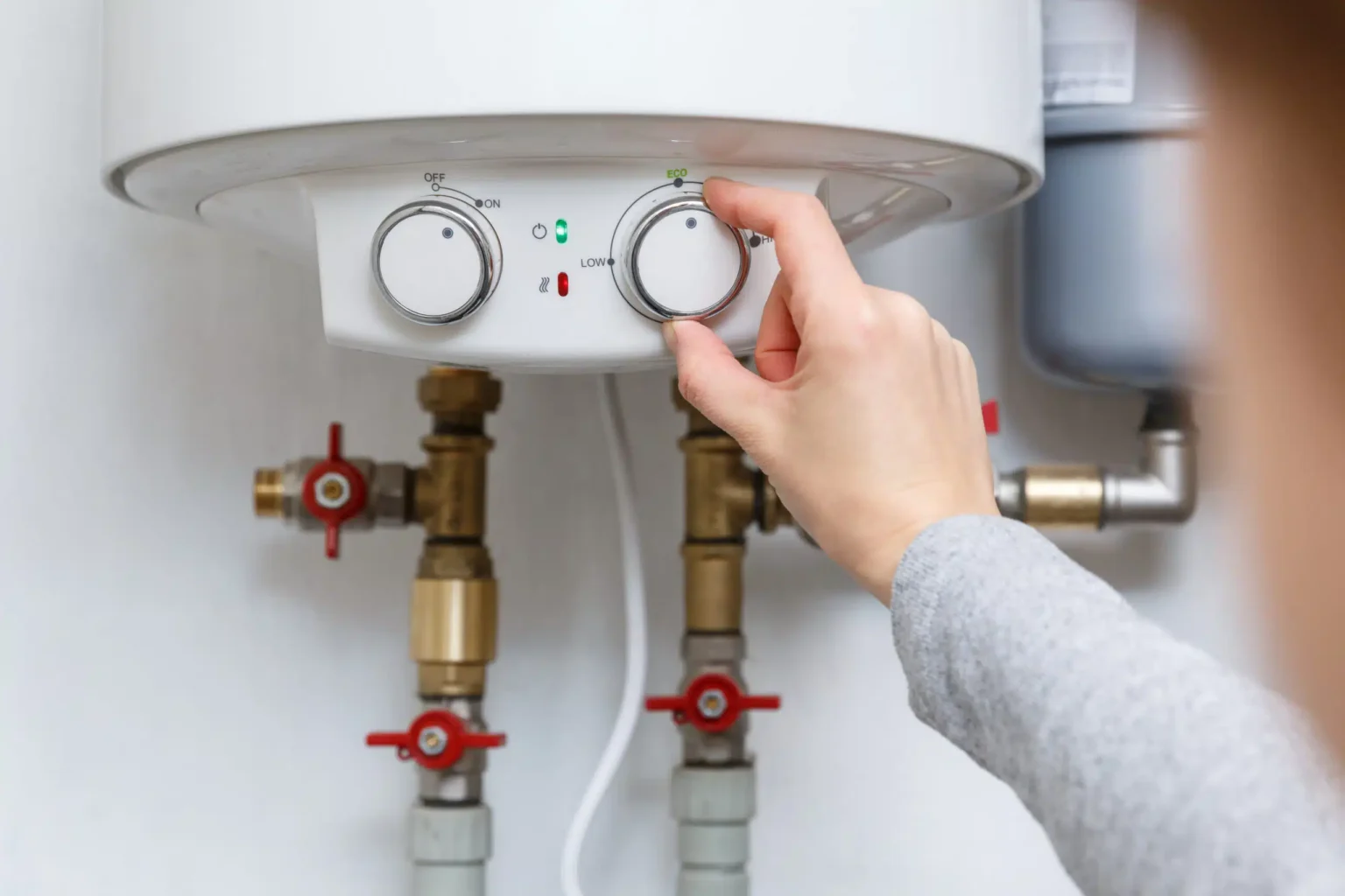 Homeowner adjusting the temperature controls on a water heater in Camas